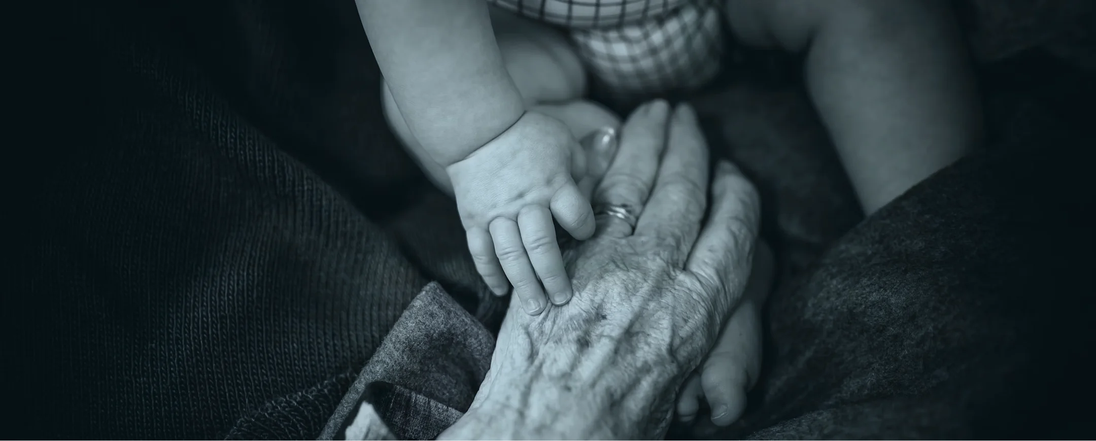 A baby's hand resting on an elderly person's hand