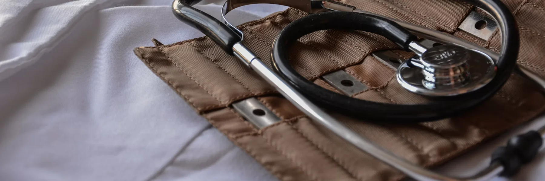 A stethoscope resting on a tan medical case